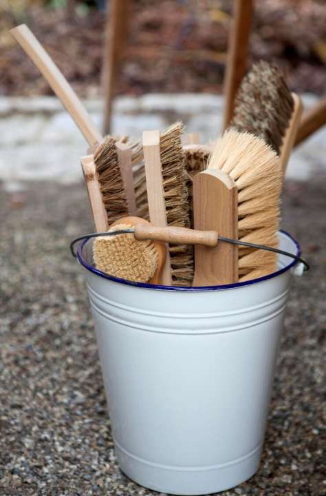 white enamel bucket filled with various cleaning brushes